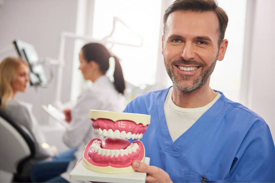 smiling-dentist-showing-artificial-dentures-1-1-1